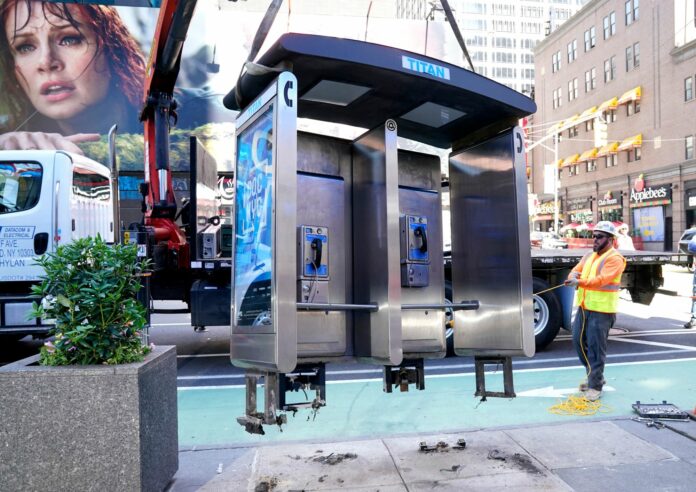 На фото: Рабочие демонтируют последний уличный таксофон Нью-Йорка, установленный вблизи перекрёстка Седьмой авеню и 50-ой улицы в центре района Манхэттен, Нью-Йорк, 23 мая 2022 года.